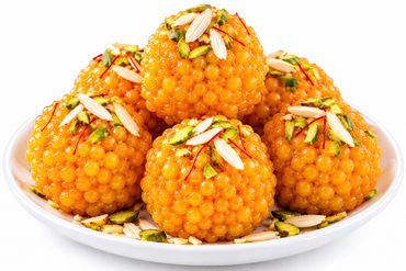 Six golden-orange gulab halwa balls topped with sliced almonds and chopped pistachios, served on a white plate against a white background.